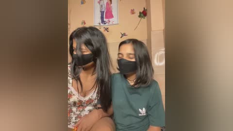 Media: Video of two young South Asian girls with dark hair, wearing floral tops and black masks, sitting close in a cozy, decorated room with butterfly stickers and a wall poster.