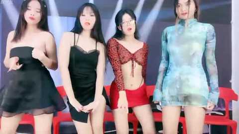 Media: Video of four East Asian women with varying skin tones and hair colors in revealing, colorful, and semi-transparent outfits, posing confidently against a backdrop of modern, abstract white and red elements.