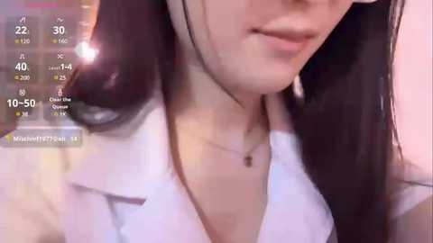 Media: A close-up video of a young woman with fair skin, wearing a white shirt, and a black necklace. The background is blurred, with a live stream overlay showing 10:50 and a chat window.