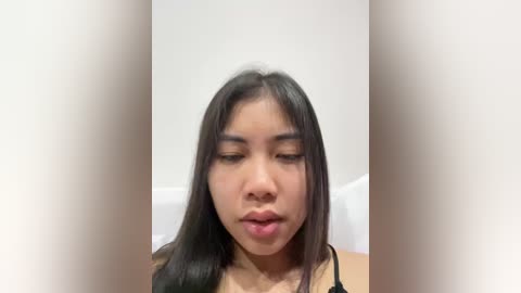 Media: Video of an Asian woman with long, straight black hair, wearing a black bra, looking contemplative with slightly parted lips, against a plain white background.