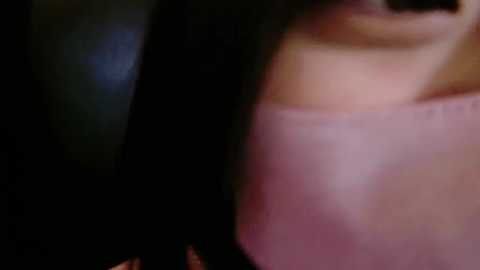 Media: Video of a close-up, blurred image showing a partially visible person with pale skin and a pink garment, possibly a shirt, against a dark background.