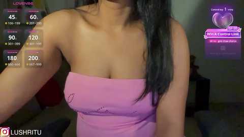 Media: Video of a woman with long black hair in a strapless pink dress, taken in a dimly lit room with a virtual reality headset display.