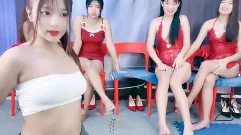 Media: Video of four Asian women in red and white lingerie, sitting on colorful chairs, wearing high heels, against a gray and blue backdrop.