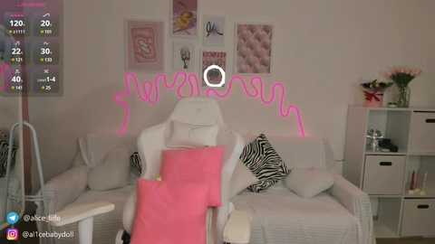 Media: A video of a modern, light-colored living room with a white leather recliner, pink blanket, and zebra-print cushions on a sofa. Pink neon lights spell \"Welcome\" on the wall.