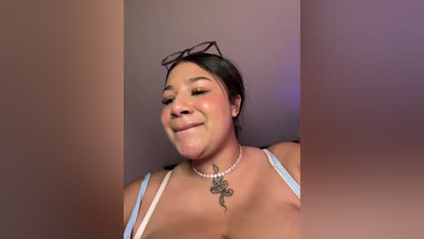 Media: Video of a Latina woman with medium brown skin, dark hair, and a small tattoo on her neck, wearing a light blue bra, smiling.