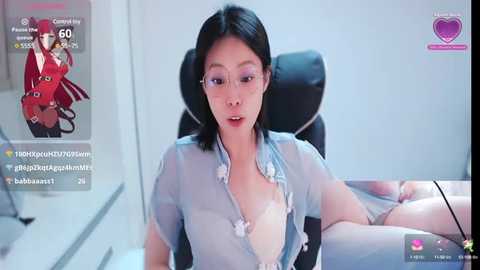 Media: A video of a young Asian woman with short black hair, wearing a sheer blue blouse revealing a pink bra. She sits in a modern office chair, with a virtual reality headset.