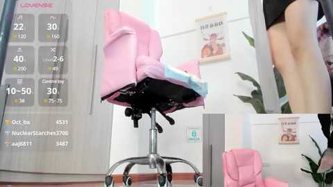 Media: Video of a pink ergonomic office chair with a blue cushion on a wooden floor, surrounded by white walls with motivational posters and a calendar.