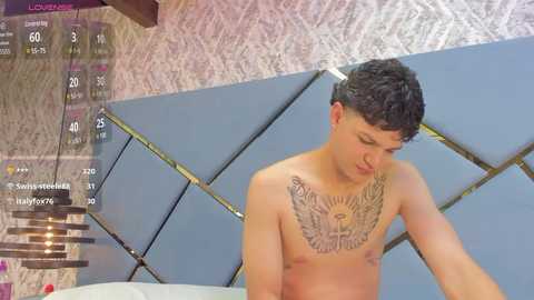 Media: Video of a shirtless young man with short dark hair and a detailed eagle tattoo on his chest, standing indoors with a tiled ceiling and wall.