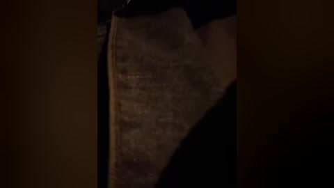 Media: Video of a close-up of an open book, showing a portion of the spine and pages. The book has a worn, aged appearance with visible stains and creases. The background is dark, creating a moody atmosphere.