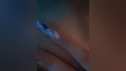 Media: A close-up video of a hand holding a cigarette, with the cigarette's glowing tip visible. The background is dark and blurry, emphasizing the hand and the lit end of the cigarette.