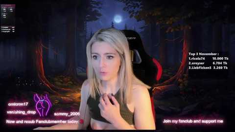 Media: A CGI screenshot of a young, fair-skinned woman with blonde hair, wearing a black top, standing in a dark, mystical forest. The image includes text overlays for a Twitch stream.