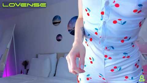 Media: Video of a woman in a white dress with cherry patterns, standing in a bedroom with a white bed, purple lighting, and space-themed wall decals.