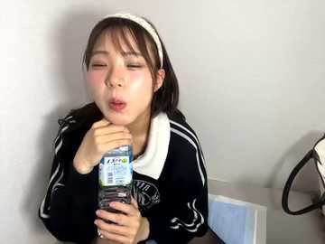 Media: Video of a young Asian woman with a white headband, wearing a black and white athletic jacket, sneezing into a tissue.