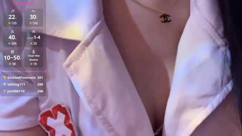 Media: Video of a woman's cleavage in a white, unbuttoned blouse with a red heart patch, revealing a necklace with a black heart pendant.