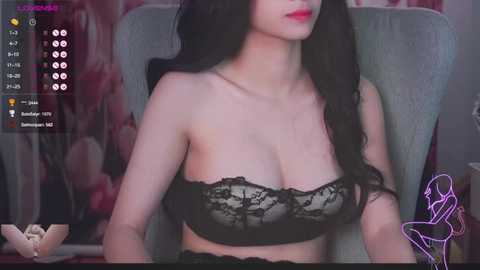 Media: Video of an Asian woman with long black hair, wearing a black lace bra, sitting in a gray chair, with a blurred floral background, and streaming platform interface overlay.