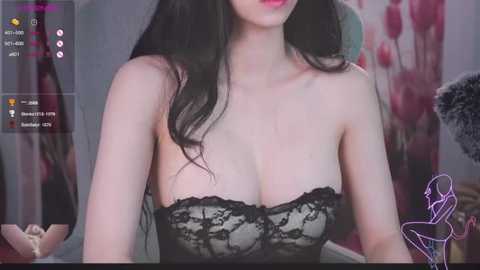 Media: Video of a young Asian woman with long black hair, wearing a black lace strapless top, in a dimly lit room with a floral wallpaper.