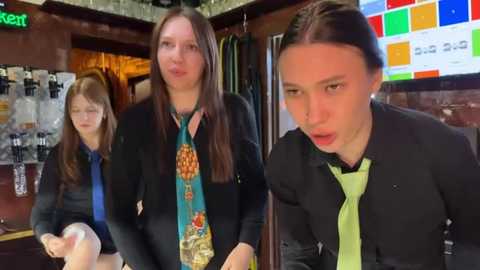 Media: Video of three women in a bar, one in a bright green tie, one in a colorful patterned tie, and one in a blue shirt, all smiling.