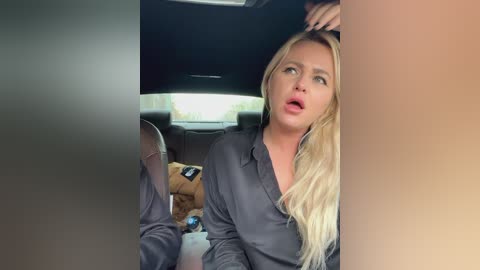 Media: Video of a shocked blonde woman in a car with a teddy bear, looking out the window.