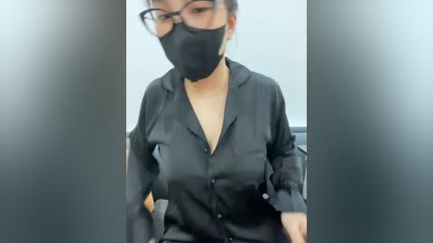 Media: Video of an East Asian woman in a black face mask, wearing glasses, a black shirt, and seated in an office chair.