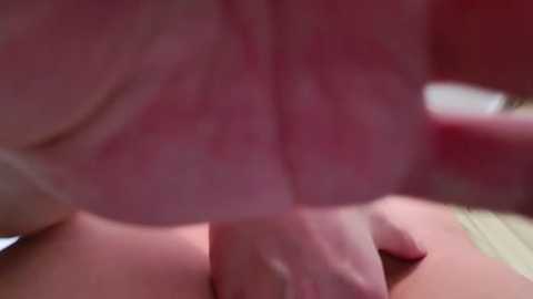 Media: Video of a close-up, blurred, reddish skin surface, possibly a nipple, with a hand partially covering it, suggesting a sexual context.