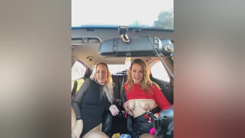 Media: Video of two women in a car, one wearing a black jacket, the other in a red top, exposing her breasts, with a blurred background.