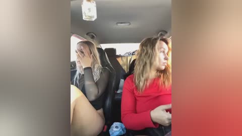 Media: Video of two women in a car: one with long blonde hair, wearing a sheer black top, crying; the other with long brown hair, wearing a red top, looks annoyed.