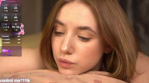 Media: A video of a young, fair-skinned, brunette woman with closed eyes, lying face down on a massage table, with a digital screen overlay showing control settings.