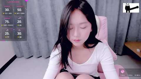 Media: A video of an East Asian woman with long black hair, wearing a white top and shorts, sitting on a pink chair, with a video overlay of exercise stats.