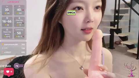 Media: A video of an Asian woman with long brown hair and light skin, holding a large, erect penis. She wears a black bra and looks at the camera. Background shows a modern, minimalistic room.