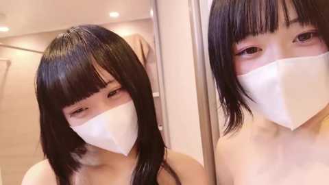 Media: Video of an East Asian woman with long, straight black hair and bangs, wearing a white surgical mask, looking slightly to the left, in a modern, brightly lit room.