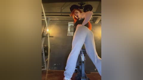 Media: Video of two women in a gym, one with long red hair wearing a black sports bra and tight white leggings, embracing the other with short black hair in tight black leggings.