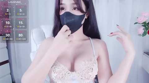 Media: A video of an East Asian woman with long black hair, wearing a black face mask and lace bra, sitting indoors.