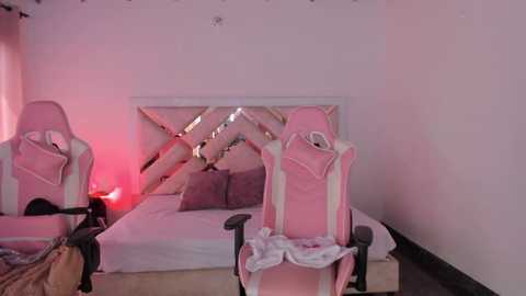 Media: Video of a pastel-themed bedroom with two pink gaming chairs, a white bed with gray pillows, and a soft pink glow.