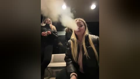 Media: Video of a blonde woman in a black leather jacket, seated at a piano in a dimly lit room, exhaling smoke from a cigarette.