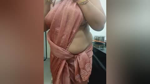 Media: A video of a woman in a pink saree, partially unbuttoned to reveal her midriff, taken in a bathroom with a sink and metallic items in the background.