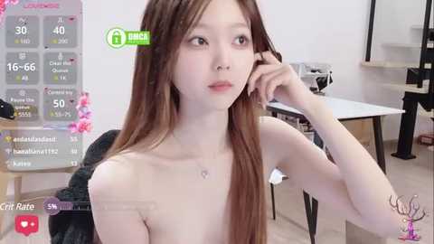 Media: A video of a fair-skinned, slim Asian woman with long brown hair, wearing a nose ring, topless, in a modern, sparsely decorated room.