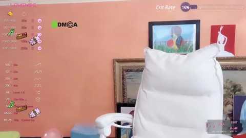 Media: A video of a cozy, peach-colored room with a large white pillow on a chair, a framed painting on the wall, and a television displaying a cartoon character.