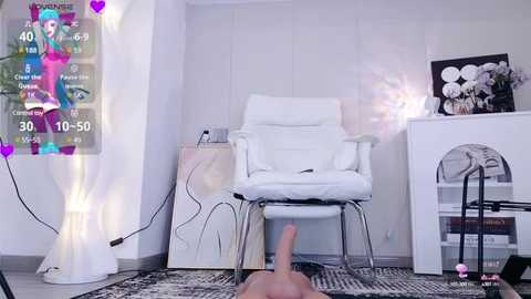 Media: Video of a modern, minimalist room with a white chair, white side table, and a digital screen displaying a woman in a colorful outfit.