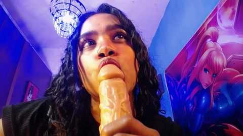 Media: Video of a person with long black hair, wearing a black top, holding a realistic, lifelike dildo, in a room with vibrant, colorful artwork on the walls.