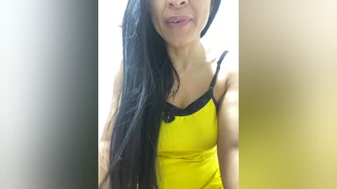 Media: Video of an Asian woman with long black hair, wearing a yellow tank top with black straps, smiling slightly.