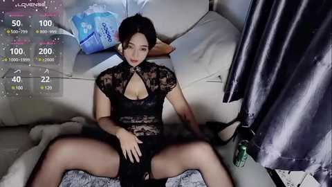 Media: A video of an East Asian woman with short black hair, wearing a black lace bodysuit, sitting provocatively on a cream sofa, with a digital health app interface in the background.