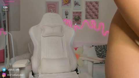 Media: Video of a white gaming chair with a cushioned back, surrounded by pink LED lighting and framed art in a girly bedroom.