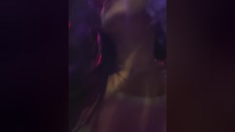 Media: Video of a blurred, motion-blurred, and darkly lit figure in a nightclub, featuring indistinct neon lights and purple hues, emphasizing the lively yet indeterminate atmosphere.