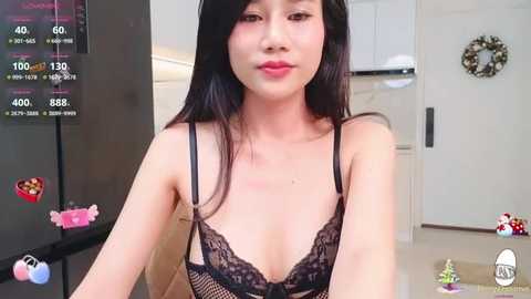 Media: A video of an Asian woman with long black hair, wearing a black lace bra, in a modern kitchen with white cabinets and a red heart decoration.