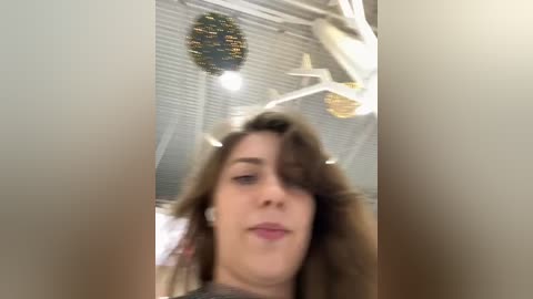 Media: Video of a woman with shoulder-length brown hair, wearing a black shirt, indoors with a ceiling fan, white blinds, and a Christmas wreath.