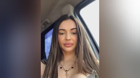 Media: Video of a young woman with long, straight brown hair, wearing a black top, and sitting in a bus. She has light skin, full lips, and a neutral expression.