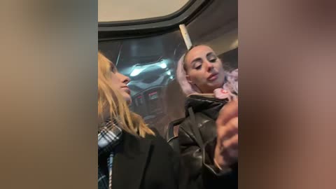 Media: Video of two women on a bus: One with blonde hair in a plaid shirt, the other with a bald head in a leather jacket.