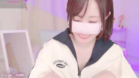 Media: Video of a young Asian woman with straight brown hair, wearing a VR headset, smiling, in a light-colored room with a white table and plant.