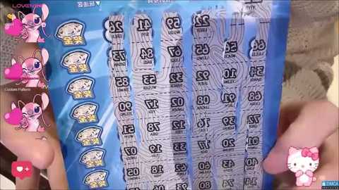 Media: A video of a person's hands holding a blue bag filled with multiple small, numbered, black-and-white cards with cartoon characters. The background features a beige couch with a plush toy.