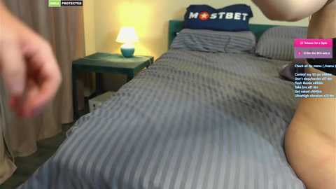 Media: A blurry video shows a woman in a bed with a blue-striped blanket, a lamp on the nightstand, and a \"MOTSEST\" pillow.